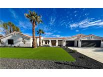 Single story home with a two-car garage, artificial turf, and palm trees at 2250 Shaw Cir, Las Vegas, NV 89117