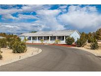 Ranch style home with a long driveway, white picket fence, and mature landscaping at 5521 Money St, Pahrump, NV 89048