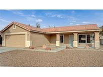 Beige house with tile roof, attached garage, and landscaped front yard at 2920 Saddle Hills Ct, North Las Vegas, NV 89031