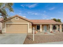 Beige house with brown tile roof, attached garage, and landscaped front yard at 2920 Saddle Hills Ct, North Las Vegas, NV 89031