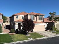 Charming two-story home with a well-manicured lawn and a beautiful tree in the front yard at 5859 Noble Stand St, Las Vegas, NV 89148