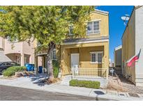 Two-story tan house with a small porch, white railing, and a mature tree in the front yard at 9140 Silk Threads Ave, Las Vegas, NV 89149