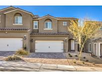 Charming two-story townhouse with a white garage door, tile roof and neat desert landscaping at 374 Yellow Finch Ln, Henderson, NV 89012