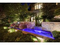An enchanting front yard with a water feature, lush landscaping, and ambient lighting creates a welcoming entrance at 641 Saint Croix St, Henderson, NV 89012