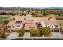 Aerial view of three houses with solar panels, landscaping, and a golf course in the background at 1172 Via Della Costrella, Henderson, NV 89011