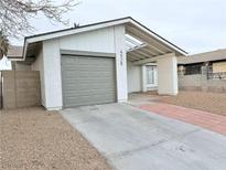 Charming single-story home featuring a gray garage door, light-colored stucco, and desert landscaping at 4928 Nellie Springs Ct, Las Vegas, NV 89110