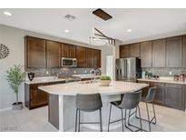 Modern kitchen features sleek countertops, stainless steel appliances and a stylish island with bar stool seating at 12898 Slipknot St, Las Vegas, NV 89141