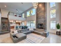 Spacious living room featuring a modern fireplace, high ceilings, and a large comfortable sectional sofa at 2680 Mystere Ct, Las Vegas, NV 89117