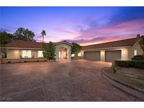 Stunning single-story home with a spacious driveway and mature landscaping at dusk at 7450 Via Olivero Ave, Las Vegas, NV 89117