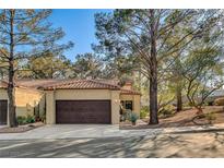 Tan stucco house with brown garage door, and mature trees at 7923 Canoe Ln, Las Vegas, NV 89145