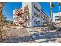 Exterior view of a two-story building with red metal stairs and landscaping at 1361 E University Ave # 209, Las Vegas, NV 89119