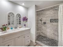 Bright bathroom with a double sink vanity and a walk-in shower featuring gray stone tiles and a pebble floor at 508 Indian Princess Dr # 101, Las Vegas, NV 89145