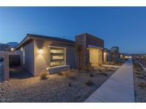 Inviting single-story home featuring desert landscaping, modern architecture, and a well-lit walkway at 888 Market Grove Ln, Las Vegas, NV 89138