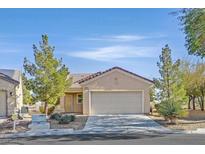 Single-story house with tan exterior, attached garage, and desert landscaping at 7568 Lily Trotter St, North Las Vegas, NV 89084