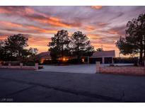 Inviting single-story home with mature trees and a spacious driveway, set against a vibrant sunset sky at 8365 Hauck St, Las Vegas, NV 89139