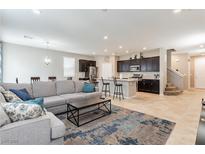 Open-concept living room flows to kitchen with dark cabinets and island seating with a modern blue area rug at 9332 Newbattle St, Las Vegas, NV 89178