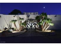 Stunning desert home exterior with palm trees and ornate iron gate at night at 7045 Edna Ave, Las Vegas, NV 89117