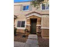 Tan two-story townhome with dark brown door, stone accents, and landscaping at 85 Day Trade St # 2, Henderson, NV 89074