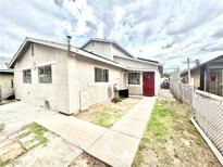 Two-story home featuring stucco siding, concrete walkway, a red door, and partial landscaping at 3620 Park Oliver Dr, Las Vegas, NV 89110