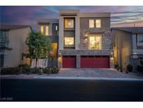 Stunning modern home featuring a stone facade and a red two-car garage, complemented by manicured landscaping at 6276 Olde Lockford Ct, Las Vegas, NV 89139