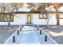 Inviting exterior featuring a vibrant front door, well-manicured landscaping, and a charming walkway at 1403 5Th Pl, Las Vegas, NV 89104