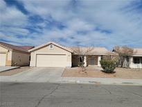 Beige one-story house with a two-car garage and landscaped front yard at 320 Mindoro Ave, North Las Vegas, NV 89031