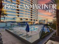 Modern building featuring a shared pool with lounge seating and stunning city views at 4565 Dean Martin Dr # 102, Las Vegas, NV 89103