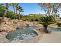 Resort-style pool with waterfall and lush landscaping at 10213 Owls Peak Ct, Las Vegas, NV 89144