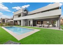 An expansive backyard shows a modern pool, well manicured grass, outdoor seating, and access to a spiral staircase at 21 Canyon Bay Dr, Henderson, NV 89011