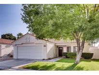 Single-story house with a white exterior, brown tile roof, and a well-manicured lawn at 5448 Red Sun Dr, Las Vegas, NV 89149