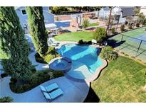 Aerial view of luxurious pool and spa, surrounded by lush landscaping and recreational amenities at 5880 W Oquendo Rd, Las Vegas, NV 89118