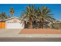 Single-story house with a white garage door and palm trees in the front yard at 6232 Lanning Ln, Las Vegas, NV 89108