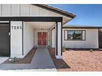 Modern house exterior with dark gray garage door and red front door at 7205 Carrondale Way, Las Vegas, NV 89128