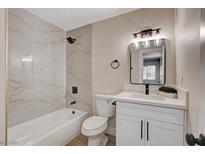 Modern bathroom featuring a tub with marble-style tile surround and a vanity with white cabinets at 4512 Mark Ave, Las Vegas, NV 89108