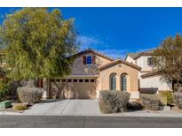 Tan two-story house with a three-car garage and landscaping at 11220 Robin Park Ave, Las Vegas, NV 89138