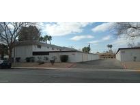 Exterior view of a light-colored building with attached garages and landscaping at 703 Greenbriar Townhouse Way, Las Vegas, NV 89121