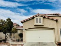 Tan two-story house with a white garage door and landscaped yard at 9708 Devenish Ave # 101, Las Vegas, NV 89129