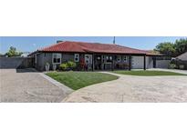 Charming gray home with a red tile roof, well-manicured lawn, and a circular driveway at 8880 W Ann Rd, Las Vegas, NV 89149