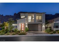 Modern two-story home with a minimalist design, balcony, desert landscaping and mountain views at twilight at 1945 Canyon Highlands Dr, Henderson, NV 89052