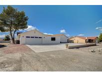 White single-story house with a two-car garage and landscaped yard at 2690 S Dandelion St, Pahrump, NV 89048
