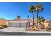 Charming home featuring a three-car garage, desert landscaping and mature palm trees at 10649 Bella Ordaz Way, Las Vegas, NV 89141