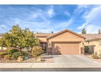 Single-story house with tan siding, landscaped yard, and two-car garage at 6128 Forest Pony Ave, Las Vegas, NV 89122