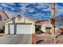 Single-story home with white garage door, solar panels, and landscaped yard at 1704 Ashburn Dr, North Las Vegas, NV 89032