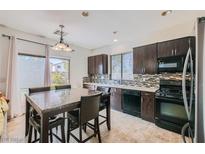 Eat in kitchen featuring dark cabinetry, stainless steel appliances, decorative tile backsplash, and a tile floor at 2905 Vigilante Ct, North Las Vegas, NV 89081