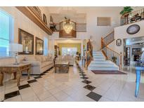 Bright living room featuring a grand staircase, large windows, and elegant tile flooring at 6632 Blue Hawaii Ave, Las Vegas, NV 89110