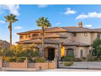 Elegant stone and stucco home featuring a gated entrance, palm trees, and well-manicured landscaping at 670 Du Fort Ave, Henderson, NV 89002