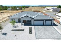 Stunning aerial view of a modern home with a gray tile roof, xeriscaped front yard, and paver driveway at 1691 Blackhorn St, Pahrump, NV 89048