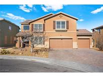 Two-story tan house with a three-car garage and a well-manicured lawn on a sunny day at 1220 Earth Ct, North Las Vegas, NV 89032