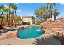 Backyard pool featuring rock waterfall, mature palms, and inviting lounge area at 4200 Topsider St, Las Vegas, NV 89129