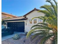 Charming single-story home featuring a black garage door, red tile roof, and desert landscaping at 9995 Yellow Canary Ave, Las Vegas, NV 89117